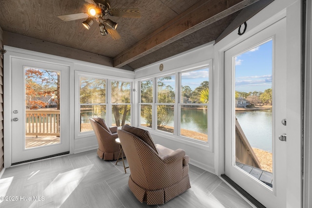 sunroom / solarium featuring plenty of natural light, beam ceiling, a ceiling fan, and a water view