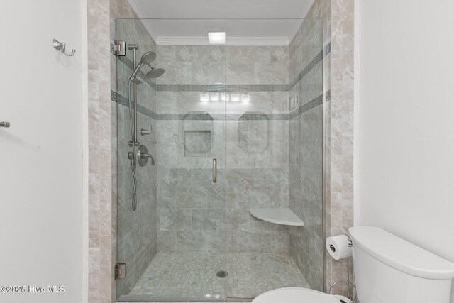 bathroom with a stall shower, toilet, and crown molding