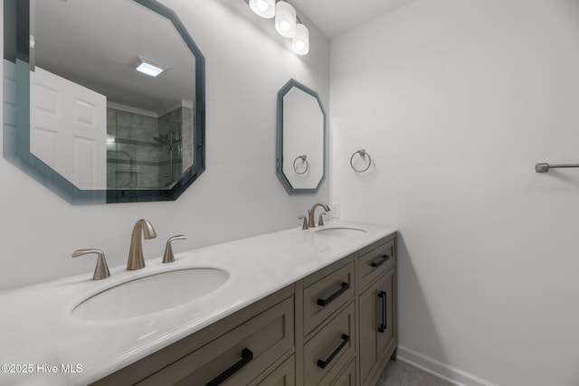 full bath with a tile shower, double vanity, baseboards, and a sink