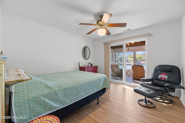 bedroom with visible vents, wood finished floors, a ceiling fan, and access to outside