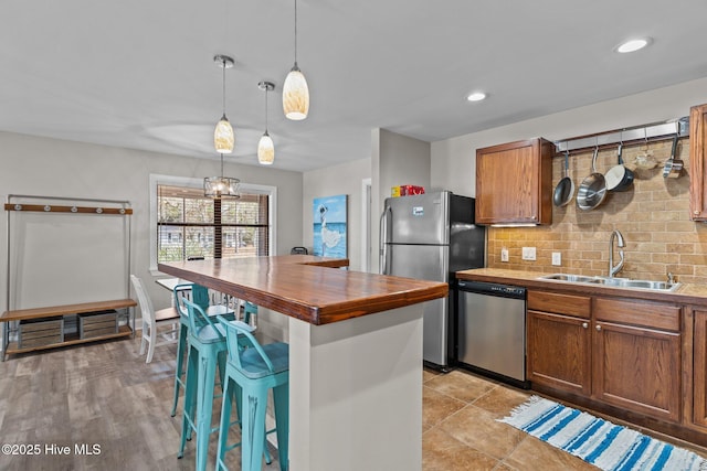 151 NE 9th St, Oak Island, NC 28465 - kitchen with stainless steel appliances, a sink, a kitchen breakfast bar, decorative backsplash, and brown cabinetry