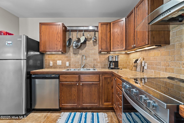 151 NE 9th St, Oak Island, NC 28465 - kitchen featuring stainless steel appliances, a sink, range hood, backsplash, and brown cabinetry