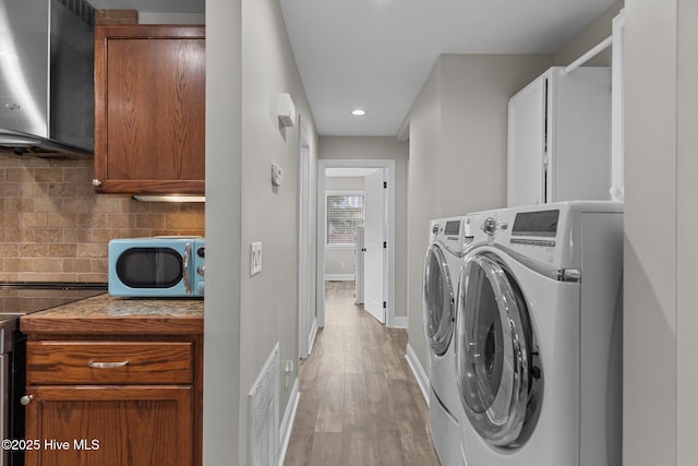 151 NE 9th St, Oak Island, NC 28465 - washroom featuring washing machine and clothes dryer, light wood-type flooring, recessed lighting, baseboards, and cabinet space