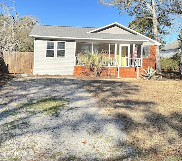 exterior space with a porch, a shingled roof, and fence