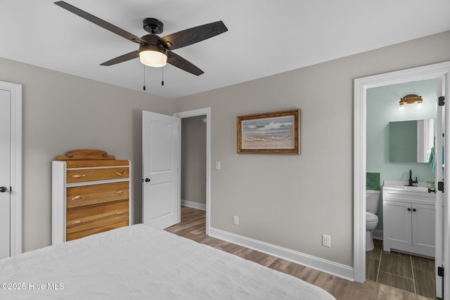 151 NE 9th St, Oak Island, NC 28465 - bedroom with wood finished floors, baseboards, a sink, and ensuite bathroom