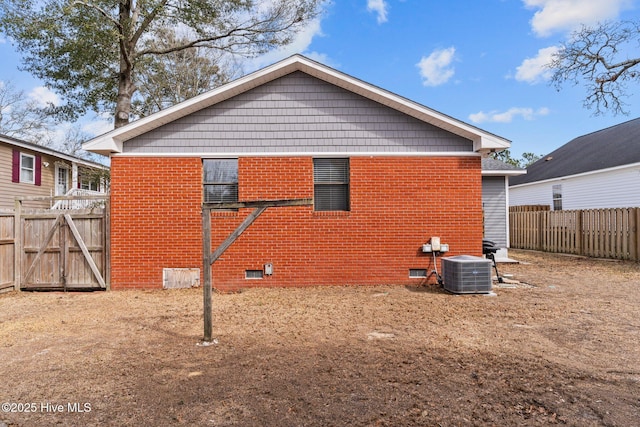 151 NE 9th St, Oak Island, NC 28465 - rear view of property featuring central AC unit, crawl space, brick siding, and a fenced backyard
