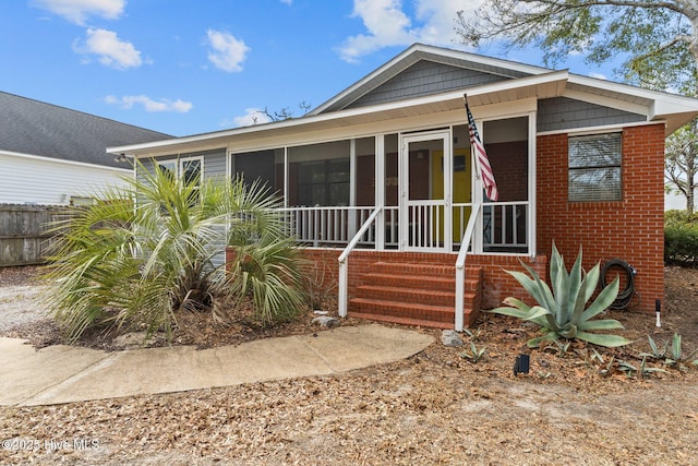 151 NE 9th St, Oak Island, NC 28465 - view of front of home with a sunroom and brick siding