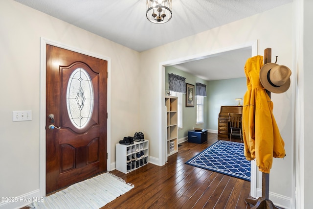 foyer entrance with baseboards, a notable chandelier, and hardwood / wood-style floors