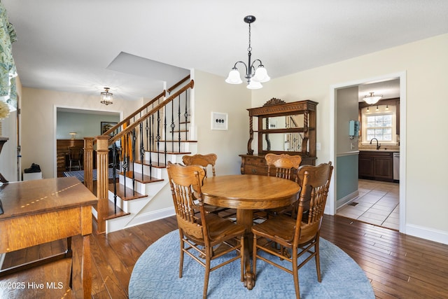 dining area with wood-type flooring, stairway, a chandelier, and baseboards