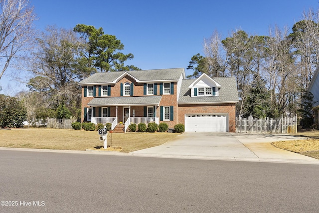 colonial-style house featuring concrete driveway, covered porch, fence, a front lawn, and brick siding