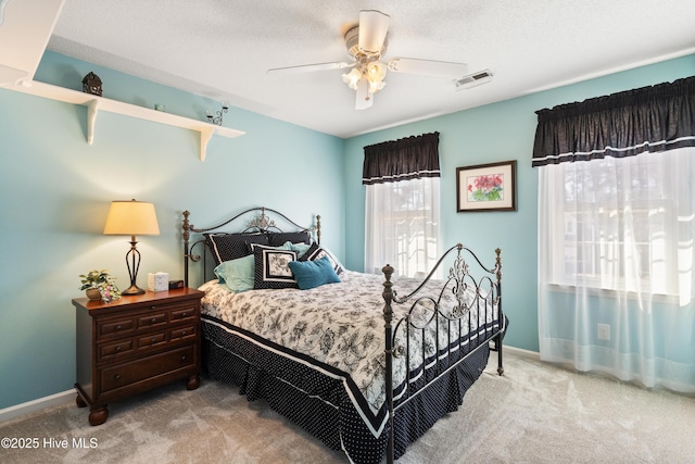 bedroom with light carpet, a ceiling fan, visible vents, and baseboards