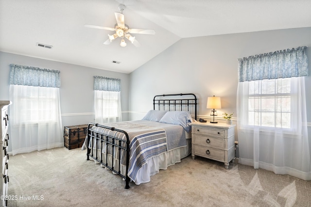 bedroom featuring light carpet, lofted ceiling, visible vents, and a ceiling fan