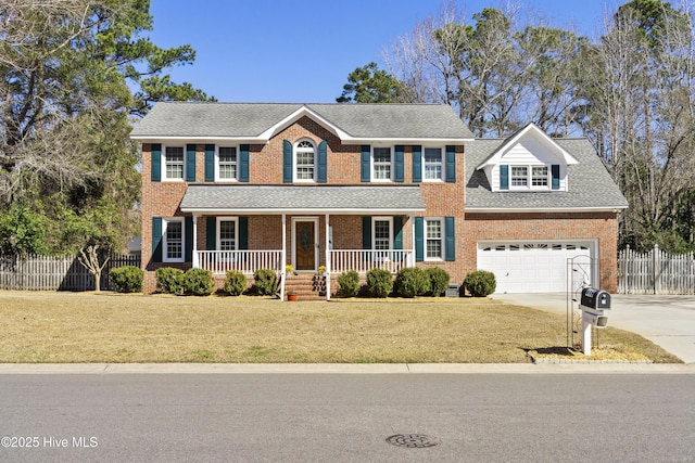 colonial home with driveway, brick siding, fence, a porch, and a front yard