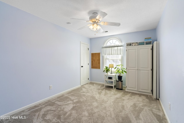 unfurnished bedroom with a textured ceiling, light carpet, a ceiling fan, visible vents, and baseboards