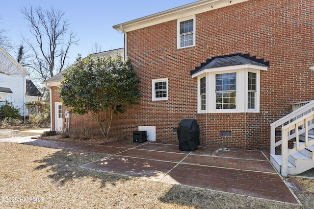 view of home's exterior with crawl space, a patio area, and brick siding