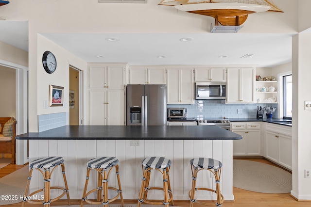 kitchen with open shelves, dark countertops, stainless steel appliances, and decorative backsplash