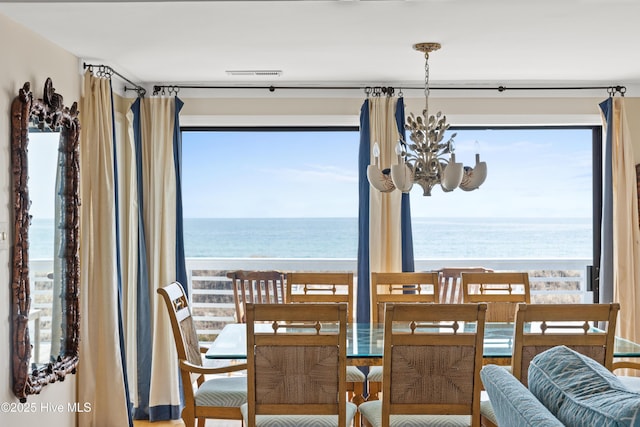 dining space featuring a chandelier, plenty of natural light, visible vents, and a water view