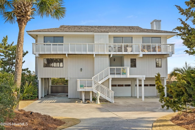 view of front of house featuring a garage, driveway, stairway, and a balcony