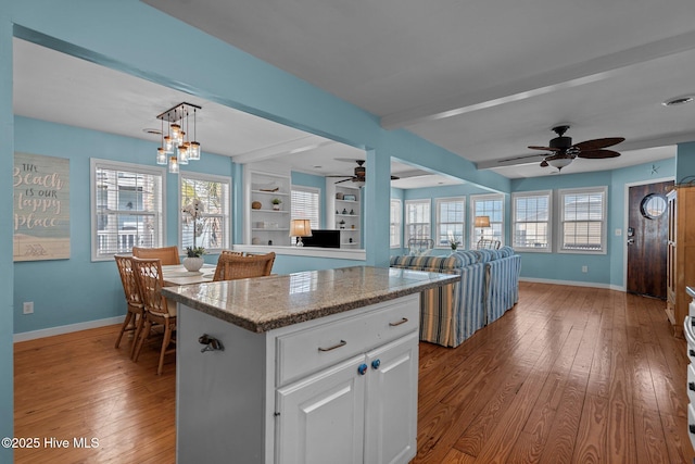 kitchen with a wealth of natural light, a center island, wood-type flooring, and baseboards