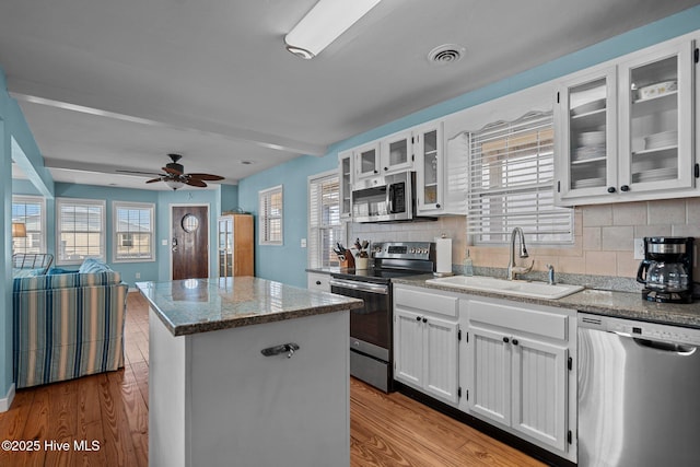 kitchen with visible vents, wood finished floors, a kitchen island, a sink, and appliances with stainless steel finishes