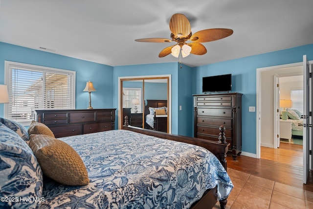tiled bedroom with a ceiling fan, baseboards, visible vents, and a closet
