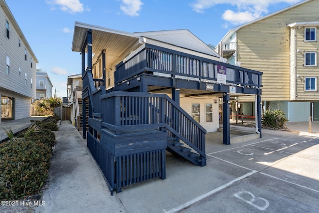 exterior space featuring stairway, a deck, and uncovered parking