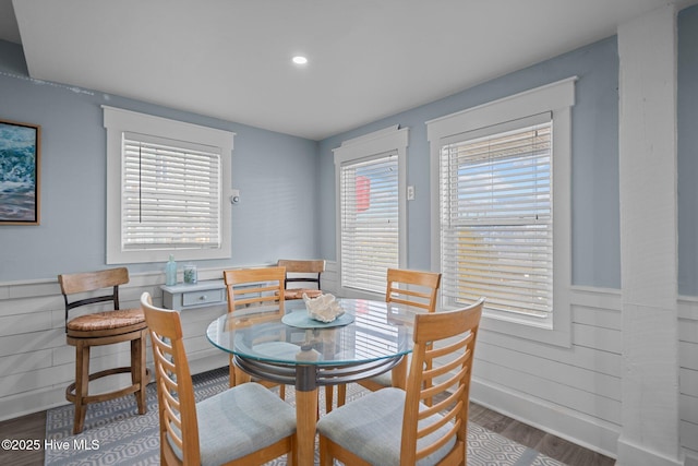 dining space with a wainscoted wall and wood finished floors