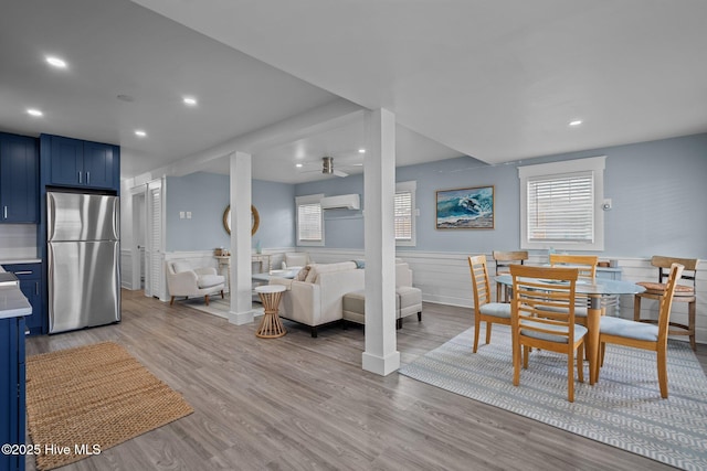 interior space featuring ceiling fan, recessed lighting, an AC wall unit, wainscoting, and light wood finished floors