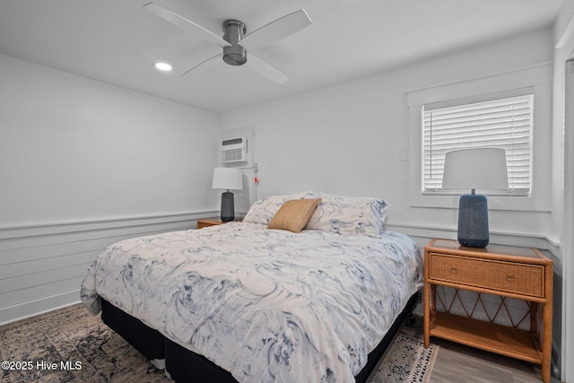 bedroom with a ceiling fan, recessed lighting, a wall mounted air conditioner, and wood finished floors