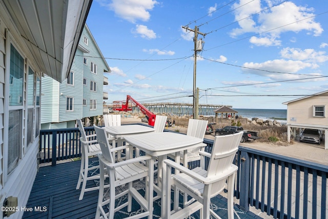 deck with outdoor dining area and a water view