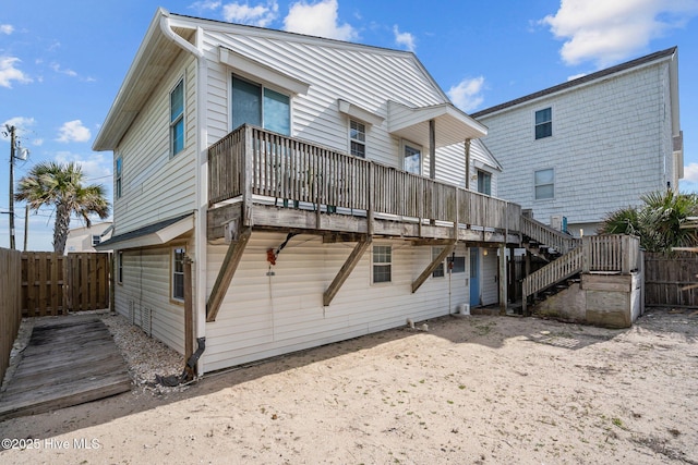 back of house featuring fence, a wooden deck, and stairs