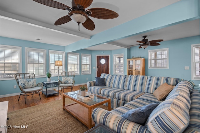 living area featuring ceiling fan, beamed ceiling, wood finished floors, and baseboards