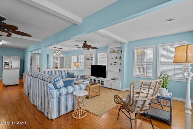 living area with beamed ceiling, ceiling fan, and light wood-type flooring