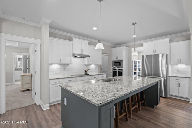 kitchen featuring under cabinet range hood, stainless steel appliances, a sink, white cabinets, and a center island with sink