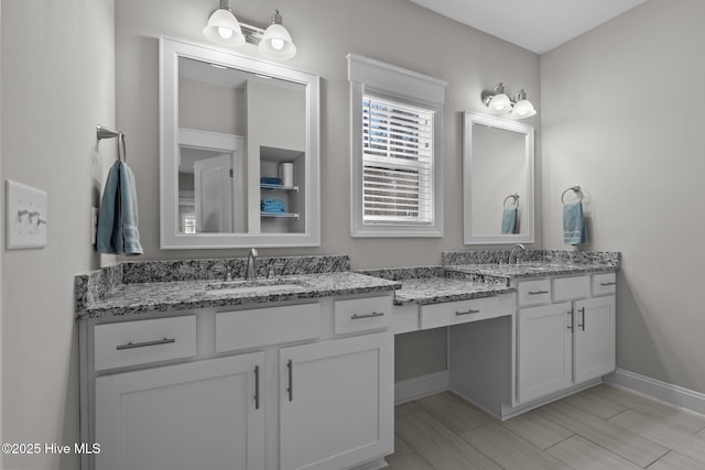 full bathroom featuring double vanity, baseboards, and a sink