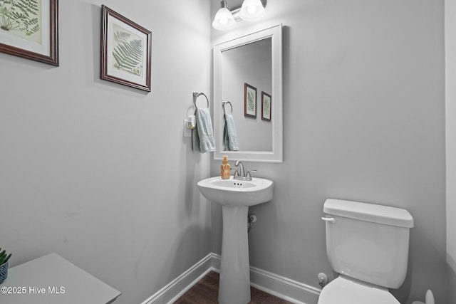 half bath featuring a sink, toilet, and baseboards