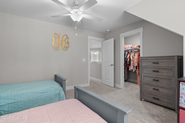 bedroom featuring light carpet, baseboards, a walk in closet, and a closet