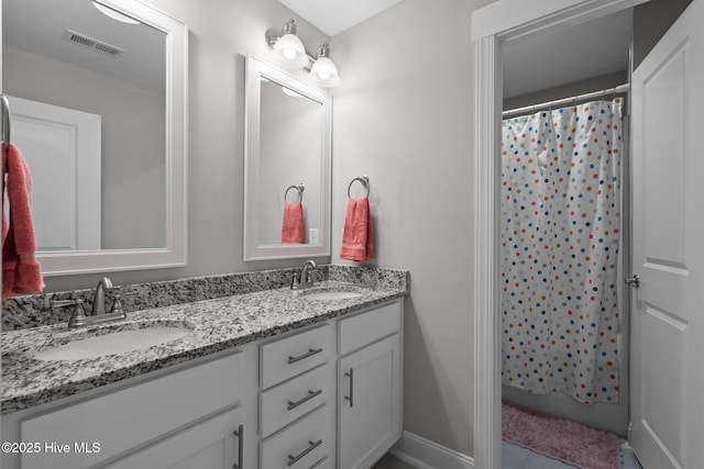 bathroom with double vanity, a sink, visible vents, and baseboards