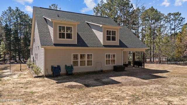 rear view of property with a shingled roof and fence