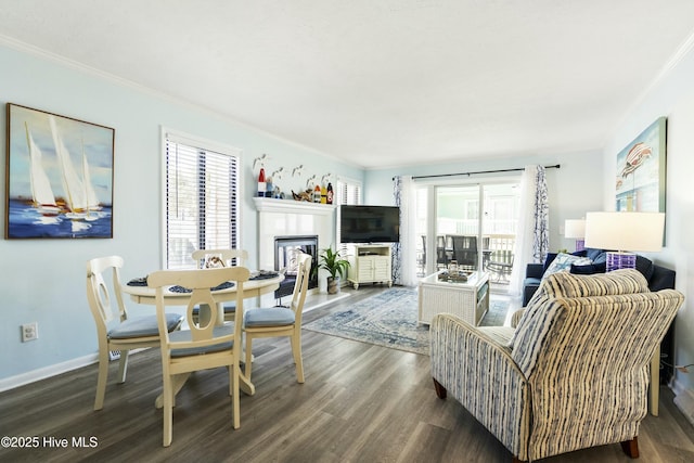 interior space featuring crown molding, baseboards, wood finished floors, and a glass covered fireplace