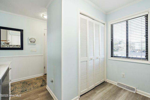 interior space with wainscoting, wood finished floors, visible vents, and crown molding