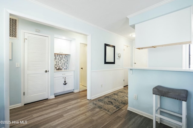 interior space with visible vents, dark wood-style flooring, crown molding, and wainscoting