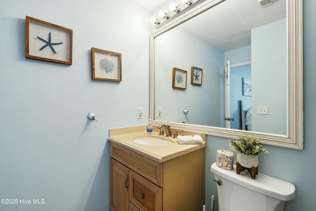 bathroom with visible vents, vanity, and toilet