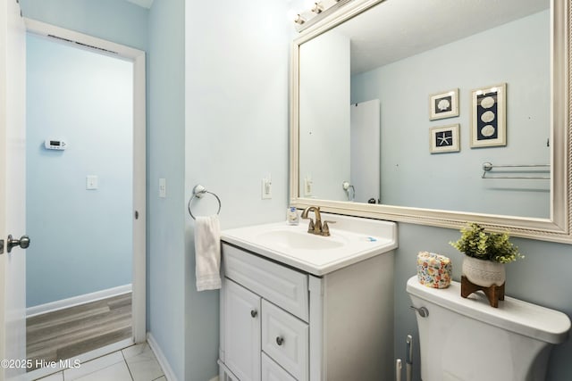 bathroom with toilet, baseboards, and vanity