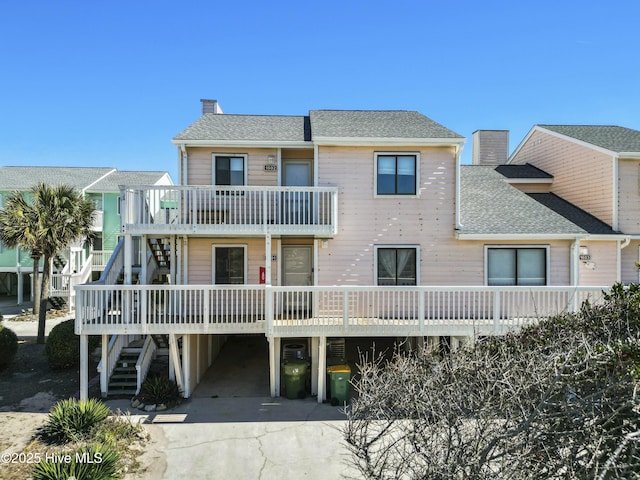 view of front of home featuring a shingled roof, a chimney, and stairway