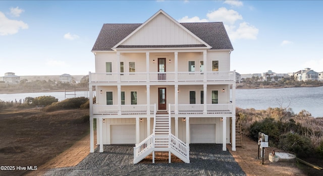 beach home with a balcony, covered porch, stairs, roof with shingles, and board and batten siding