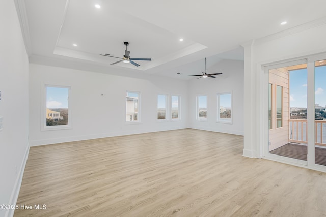 unfurnished living room with light wood-type flooring, a tray ceiling, and a wealth of natural light