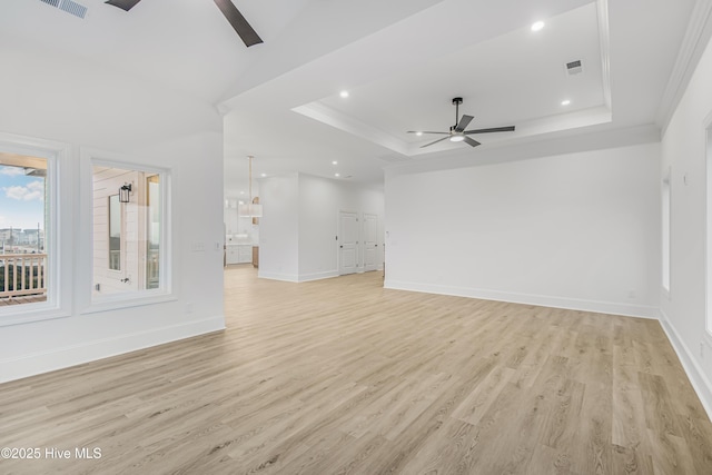 unfurnished living room with visible vents, a raised ceiling, a ceiling fan, crown molding, and light wood-style floors