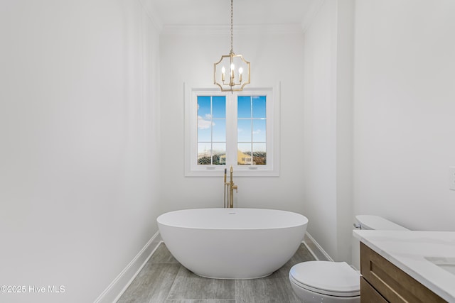 bathroom with baseboards, toilet, wood finished floors, vanity, and a freestanding tub