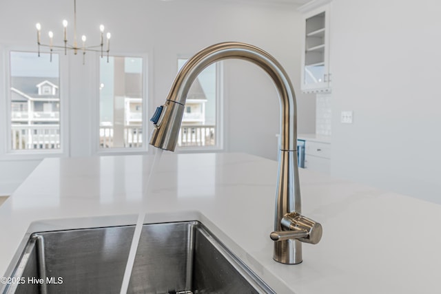 interior details with glass insert cabinets, light countertops, white cabinets, and a sink